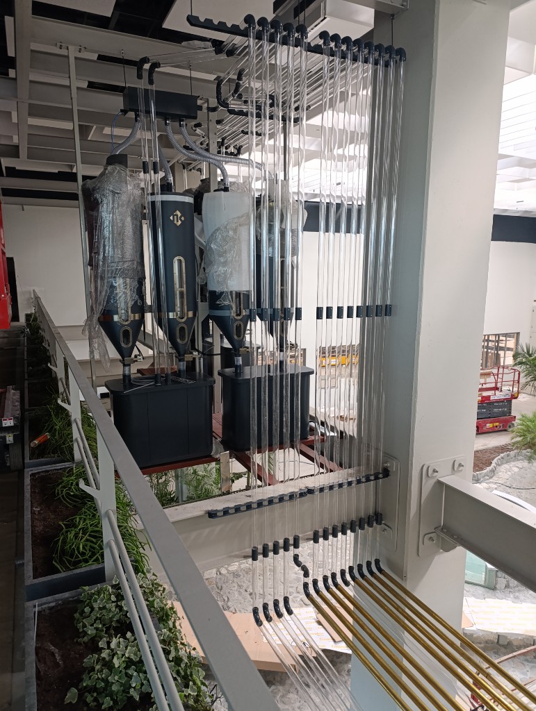 Open roastery atrium with overhead pneumatic coffee conveying pipes