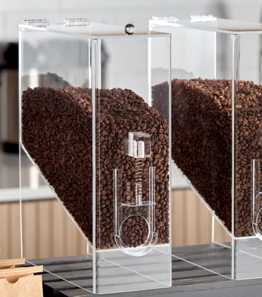 Row of decorative transparent coffee bean dispensers behind a café counter